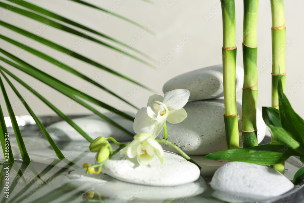 Naklejka premium Spa stones, orchid and bamboo branches in water. Space for text