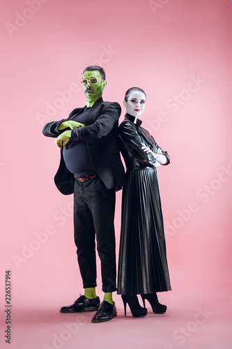 Halloween Family. Happy couple in Halloween Costume and Makeup. Bloody theme: the crazy maniak faces on pink studio background