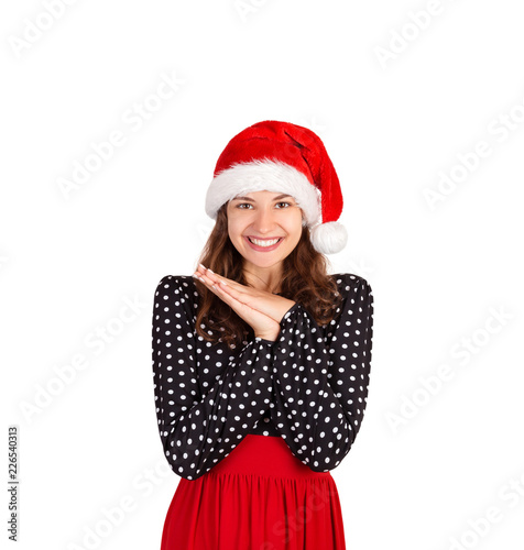 satisfied and dreamy female laughing joyfully holding palms near heart and gazing up from happiness and joy. emotional girl in santa claus christmas hat isolated on white background. holiday concept