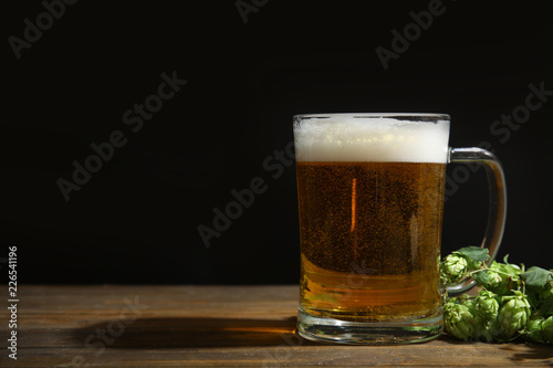 Composition with tasty beer and fresh green hops on wooden table. Space for text