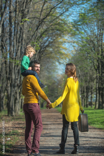 Fototapeta Naklejka Na Ścianę i Meble -  Father, mother and child go on trip. Parents and little son in park having fun on family vacation. Wish us a good trip
