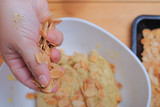 Close up of female hands making hazelnut cookies from sliced almonds and flour with coffee powder .
