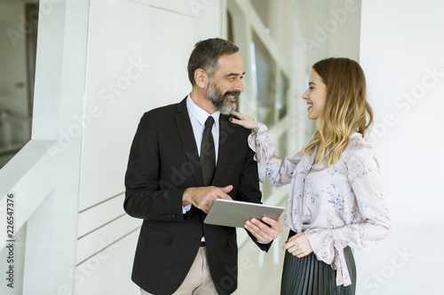 Young businesswoman and businessman look on digital tablet and discuss aout project