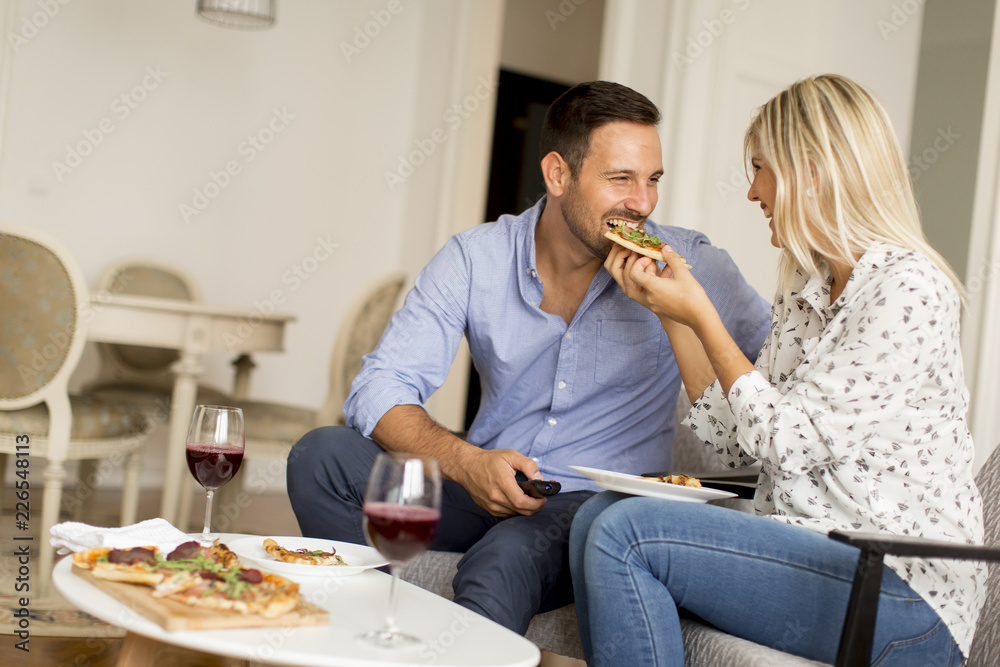 Couple relaxing at home and eating tasteful pizza Couple relaxing at home and eating tasteful pizza