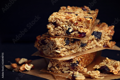 Homemade granola bars with nuts and cranberries over black background