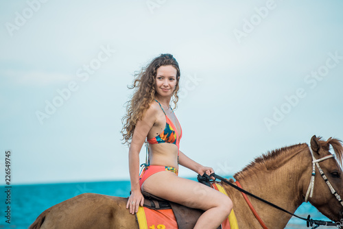 Pretty young lady riding a horse on the beach background of the sea