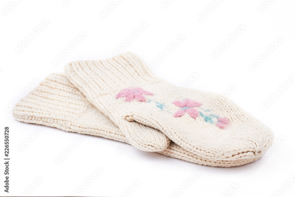White woman knitted mittens, white background. Pair of female warm mittens with a flowers embroidery isolated on white background. Ladies winter handmade fashion accessory. White woman knitted mittens, white background. Pair of female warm mittens with a flowers embroidery isolated on white background. Ladies winter handmade fashion accessory.