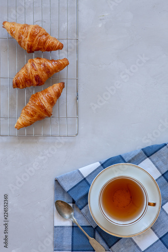 Fresh tasty croissants and cup of tea, on concrete grey table. Top view, close-up, background.