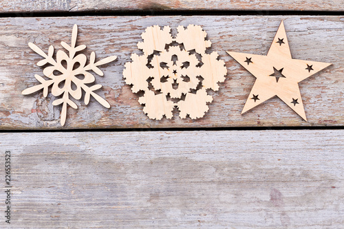 Cut out wooden Christmas decoration figures. Carved wooden snowflakes and star on old rustic wooden background, copy space.