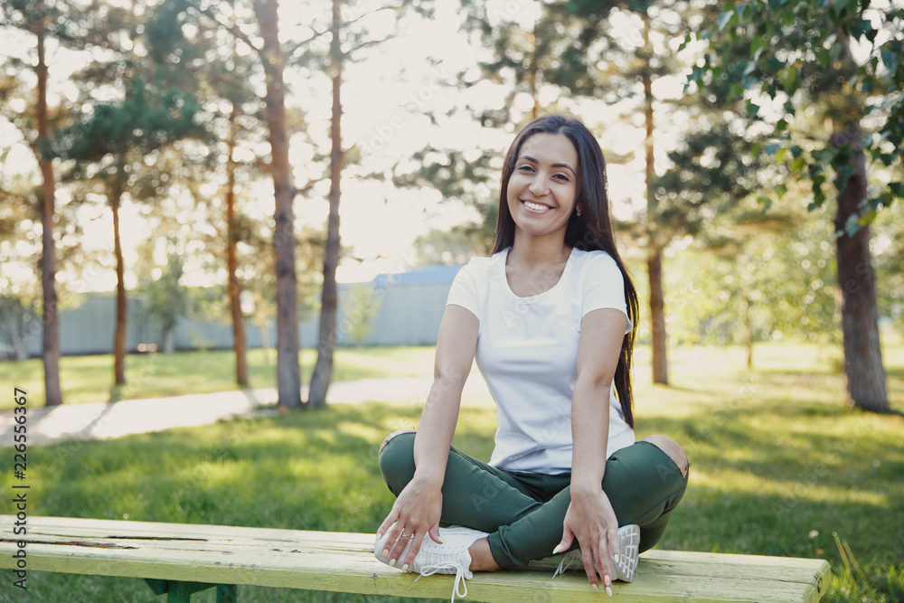 Young beautiful woman sitting on bench in park. Pretty girl at outdoors on summer day. Nature environment background. Young beautiful woman sitting on bench in park. Pretty girl at outdoors on summer day. Nature environment background.