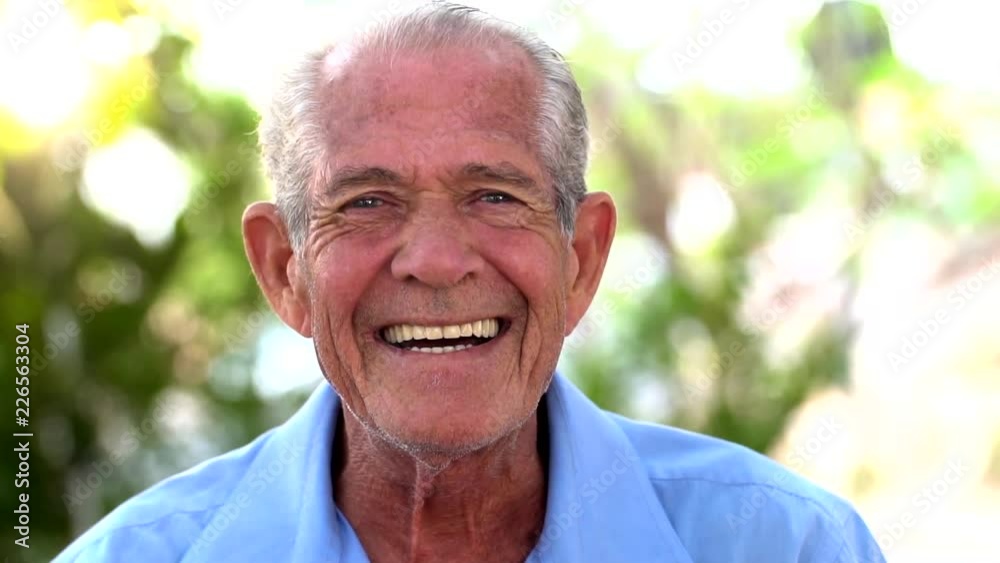portrait of senior brazilian man with white hat looking at camera and one spot in sunset and smiling. Horizontal shape, copy space