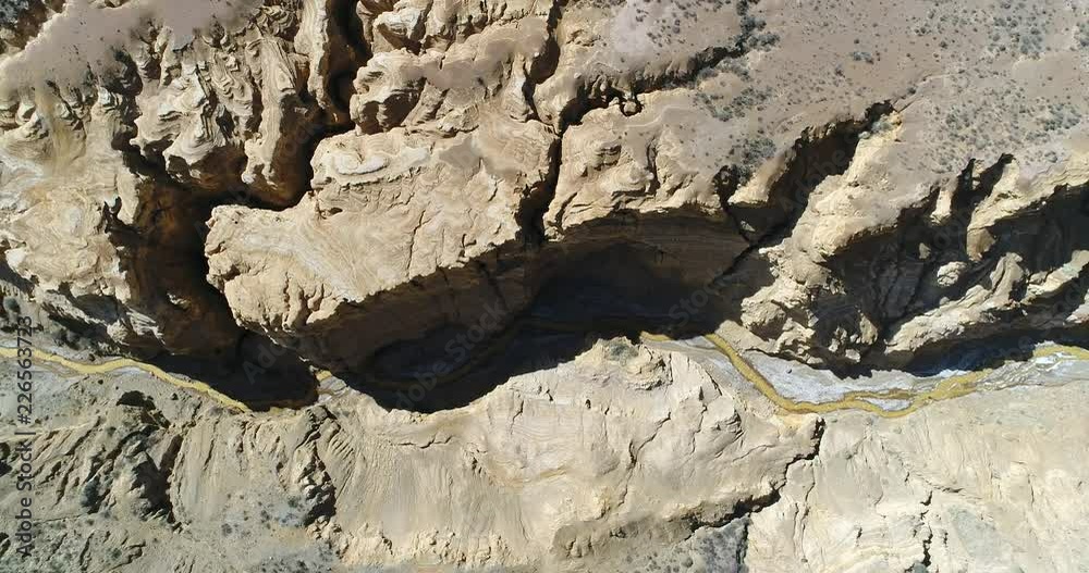 Aerial senital drone scene of Ocre Canyon in Famatina Mountains and Yellow river. Camera ascends. General view of canyon with gullies, golden river, cliff and eroded landscape. La rioja, Argentina Aerial senital drone scene of Ocre Canyon in Famatina Mountains and Yellow river. Camera ascends. General view of canyon with gullies, golden river, cliff and eroded landscape. La rioja, Argentina