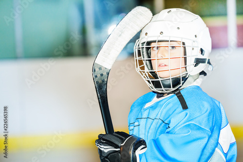 Little hockey player in helmet and blue uniform