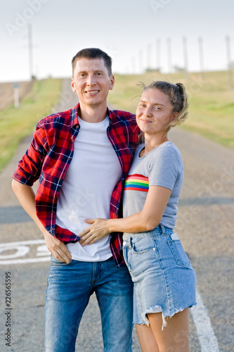 Young happy smiing couple standing by a county road