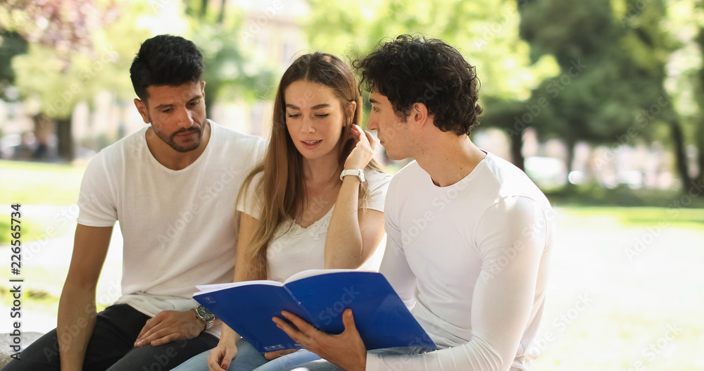 Three students studying together sitting on a bench outdoor