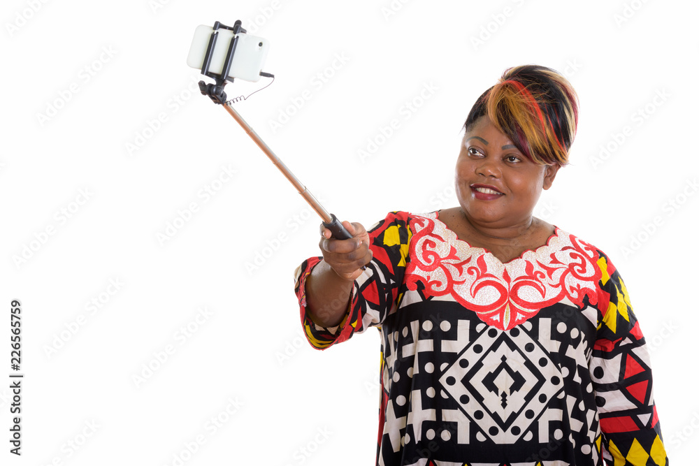 Studio shot of happy fat black African woman smiling while holdi Studio shot of happy fat black African woman smiling while holdi