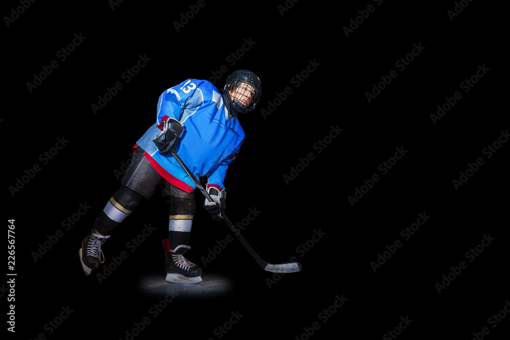 Ice hockey player with stick over black background