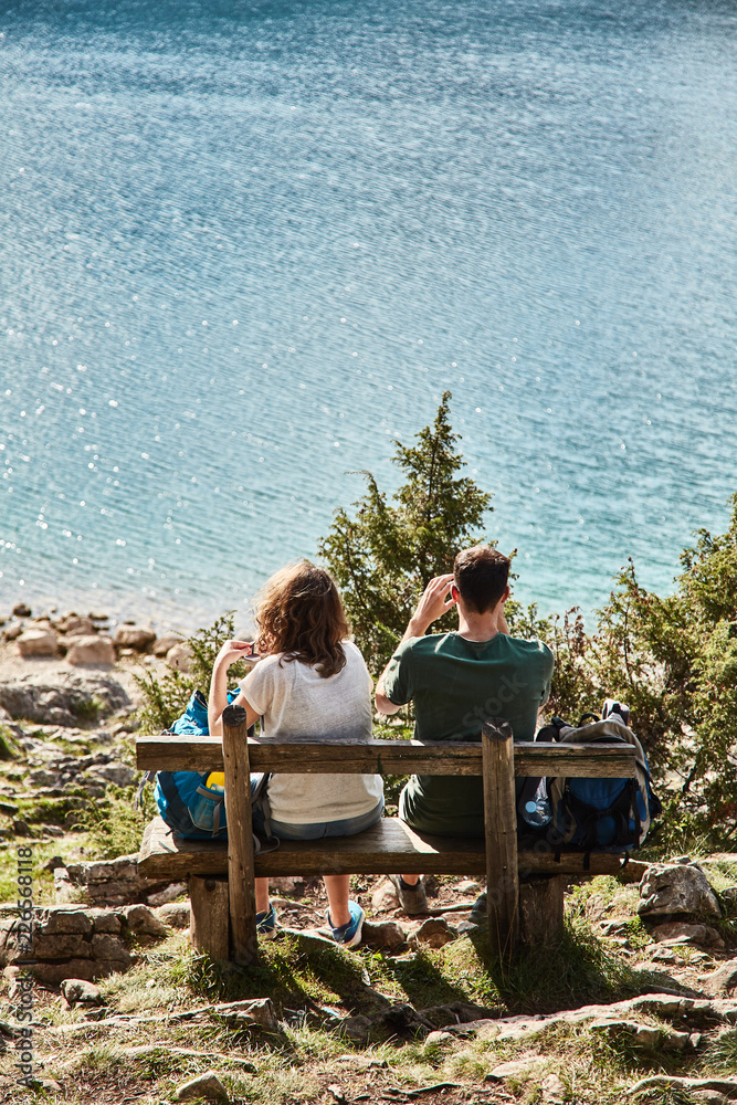 A young couple sitting on a bench. Black lake. Durmitor national Park. Montenegro. 