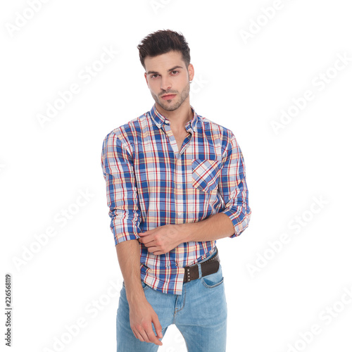 portrait of seductive man fixing his plaid shirt sleeve