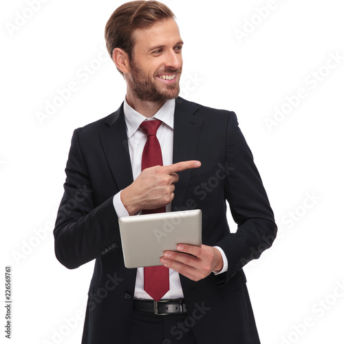 curious businessman with tablet looks and points to side