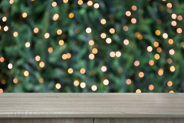 Blurred gold garland on Christmas tree as background and wooden tabletop as foreground. Christmas abstract. Image for display or montage your christmas products. Copy space.