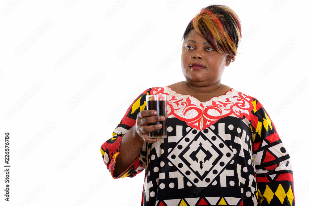 Studio shot of fat black African woman holding glass of soda dri