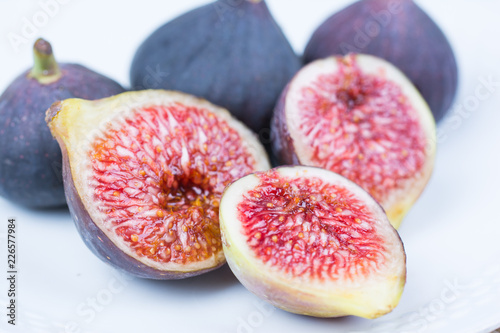 Fresh figs. Vegetarian Food. Whole and sliced figs on a white plate on white background. Copy space. Close up.