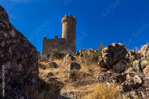 Footpath heading upwards to a medieval watchtower under a blue sky (Torrelodones, Spain) photo