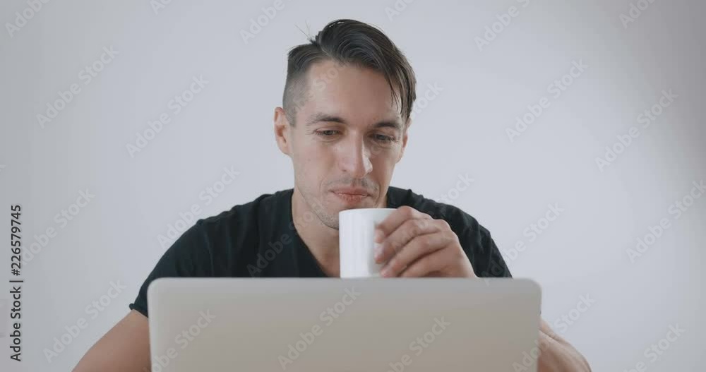 Young businessman working at laptop and drinking coffee on white background. Young businessman working at laptop and drinking coffee on white background.