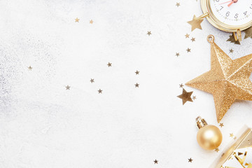 Christmas or New Year composition, gray background with gold Christmas decorations, stars, snowflakes, balls, alarm clock, gift box, top view