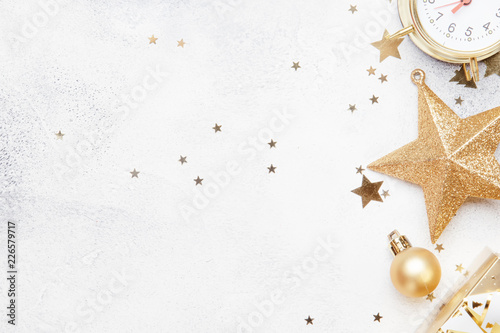 Christmas or New Year composition, gray background with gold Christmas decorations, stars, snowflakes, balls, alarm clock, gift box, top view