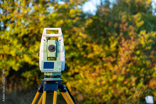 Surveyor equipment (theodolit or total positioning station) on the construction site of the motorway or road with bush in background during sunrise