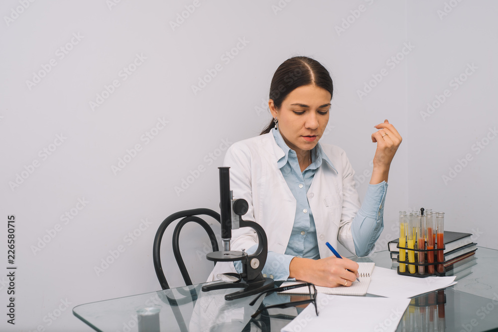 Beautiful medical doctors in gloves and glasses are working with substances in test tubes and microscope at the lab. Photo of attractive concentrated female doctor writing prescription on special form Beautiful medical doctors in gloves and glasses are working with substances in test tubes and microscope at the lab. Photo of attractive concentrated female doctor writing prescription on special form