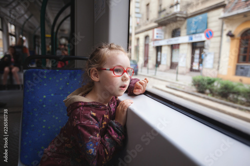 Photography a young girl is riding in a tram and looks with curiosity on the sides
