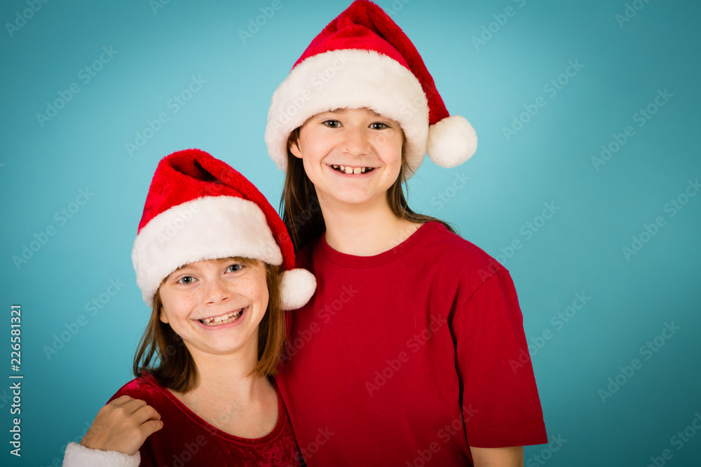 Happy Christmas Girls in Santa Hats, Isolated on Teal Happy Christmas Girls in Santa Hats, Isolated on Teal