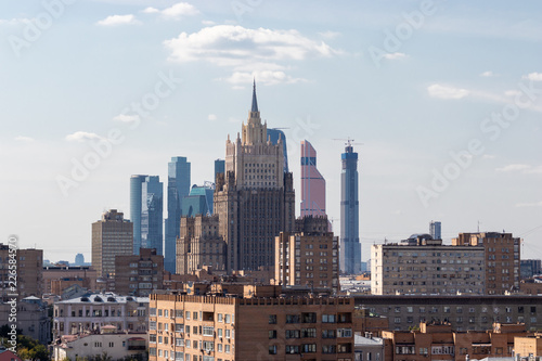 Modern buildings on the background of old buildings. Several eras in one photo. Big city on a background of blue sky. A tall building touches the spire of white clouds. Moscow City.