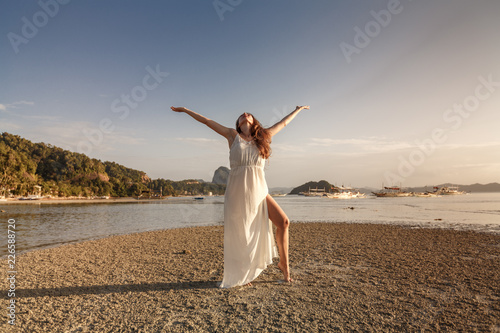 Woman in white dress at the sea on the sunset on Palawan island, Philippines