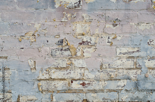 Pastel paint chips away from brick wall