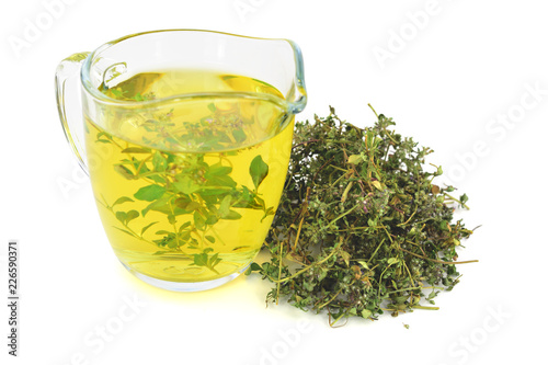 A Glass of Wild Thyme (Thymus) Tea Extract with a Heap Pile of Dried Herb. Isolated on White Background. photo