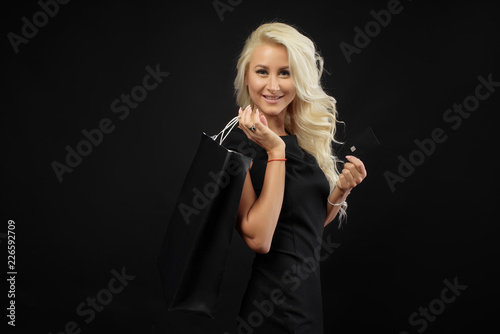Shopping woman holding bag isolated on dark background in black friday holiday