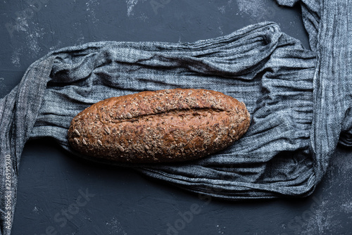 Whole grain bread with seeds on a gray fabric on a textured surface. Flat lay