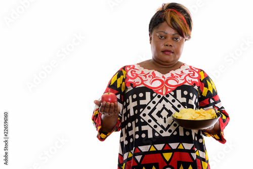 Studio shot of fat black African woman holding red apple and bow