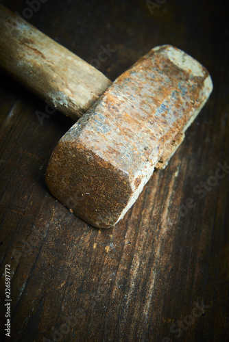 Close up of old used hammer on a rustic wooden background. Selective focus