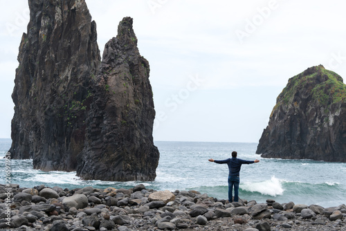 Man with arms wide open looking at Ribeira da Janela islet in Madeira