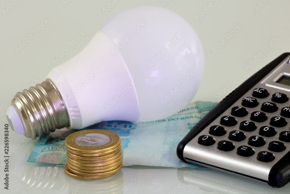 Real hundred notes, real coins and a lamp. Brazilian money. Energy Brazil. Real hundred notes, real coins and a lamp. Brazilian money. Energy Brazil.
