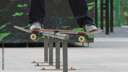 Skater make trick boardslide on rail in skatepark, close-up view in slowmotion photo