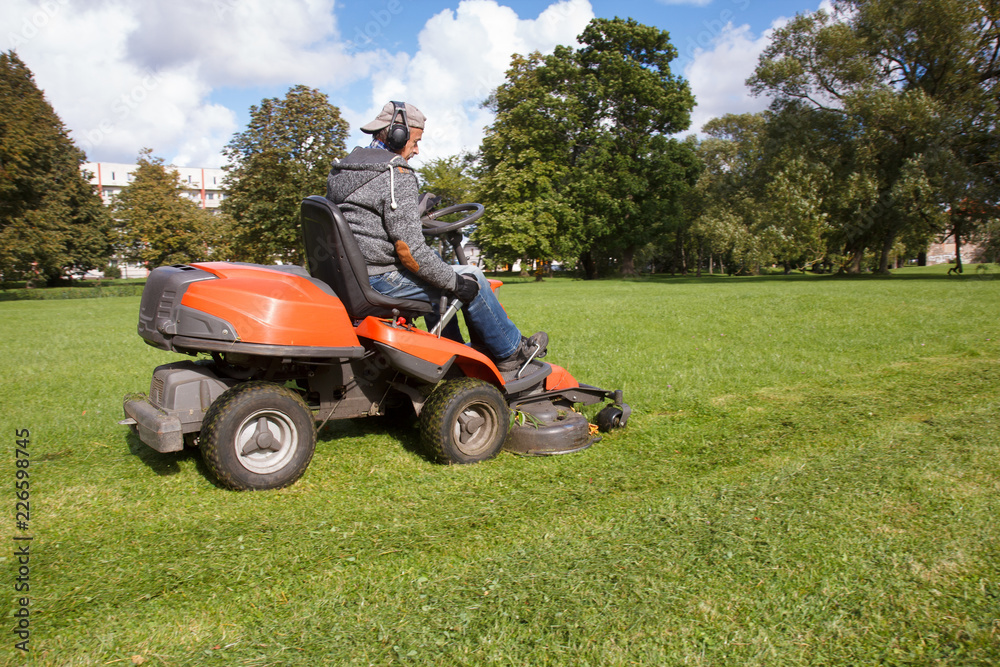 lawn mower tractor working in the town park lawn mower tractor working in the town park