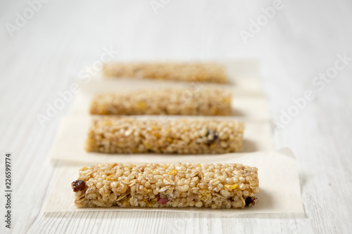 Granola bars on baking sheet over white wooden surface, side view. Close-up. Selective focus.