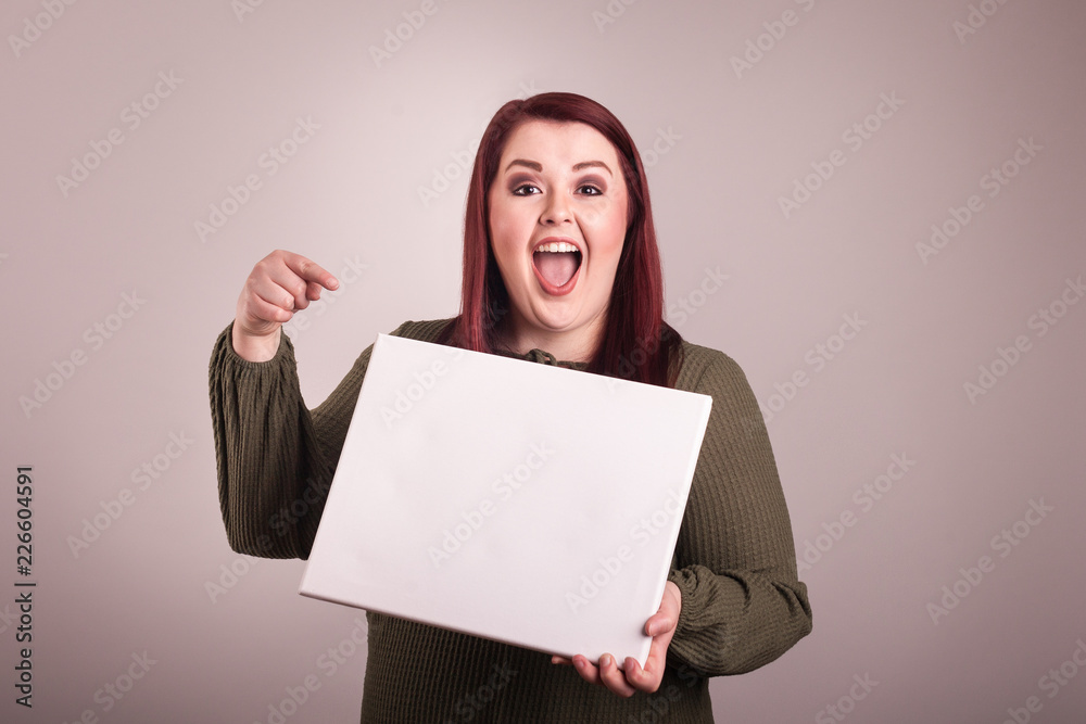 Woman holding a blank board pointing a finger at blank sign excited happy facial expression - obrazy, fototapety, plakaty 