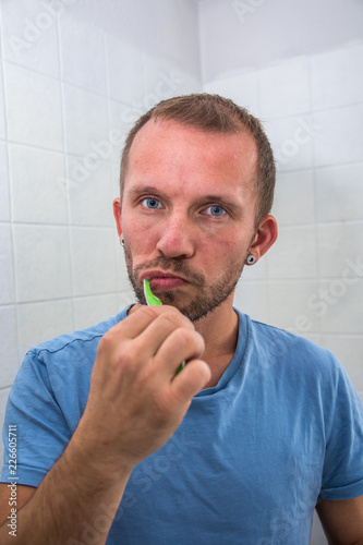 Mann beim Zähneputzen im Badezimmer (Hochkant)